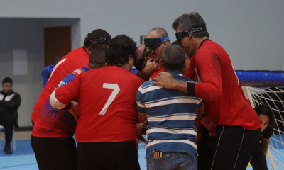 Jogadores de goalball reunidos no meio da quadra