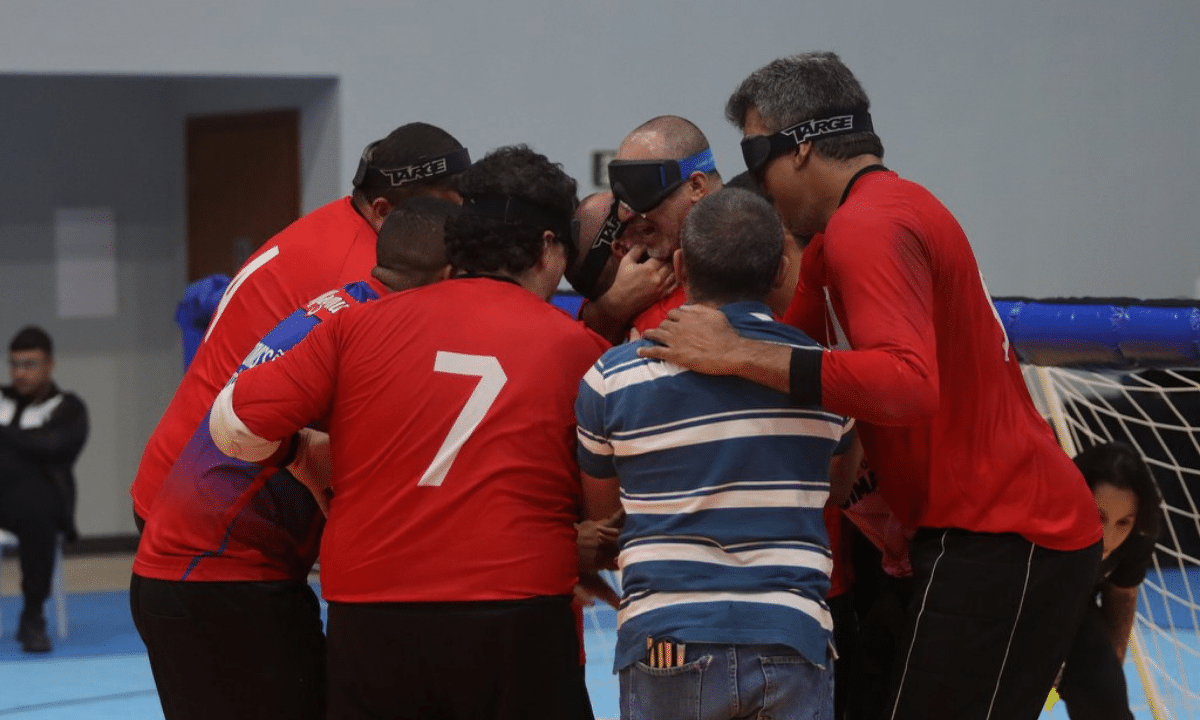 Jogadores de goalball reunidos no meio da quadra