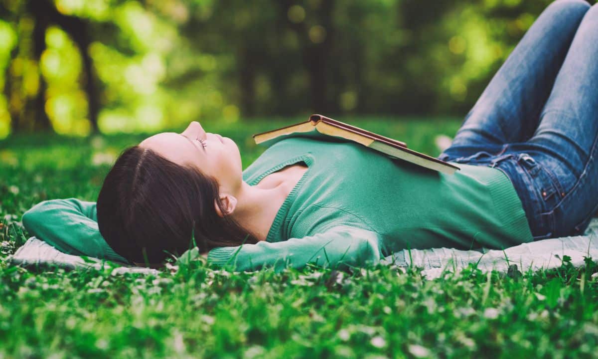 Foto horizontal de uma pessoa descansando em um sofá ou poltrona durante a tarde, com luz natural suave entrando pela janela