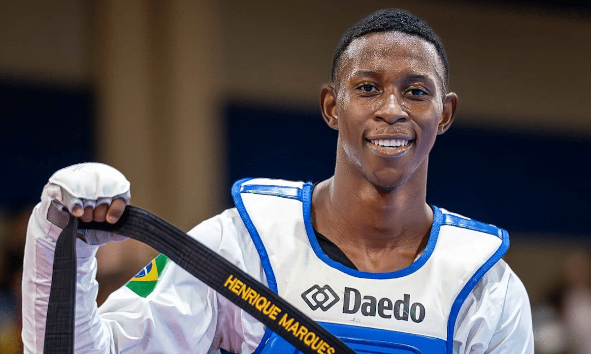 Henrique Marques, do taewkondo, sorri, e segura faixa com seu nome (Foto: dani_visuals)