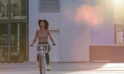 Ciclista pedala com mãos apoiadas no guidão, cotovelos levemente flexionados e ombros relaxados.