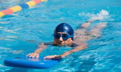 Pessoa nada crawl em piscina com destaque para a pernada e o alinhamento do quadril na água.