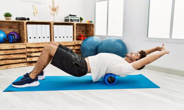 Pessoa usa foam roller na coxa antes ou depois de um treino.