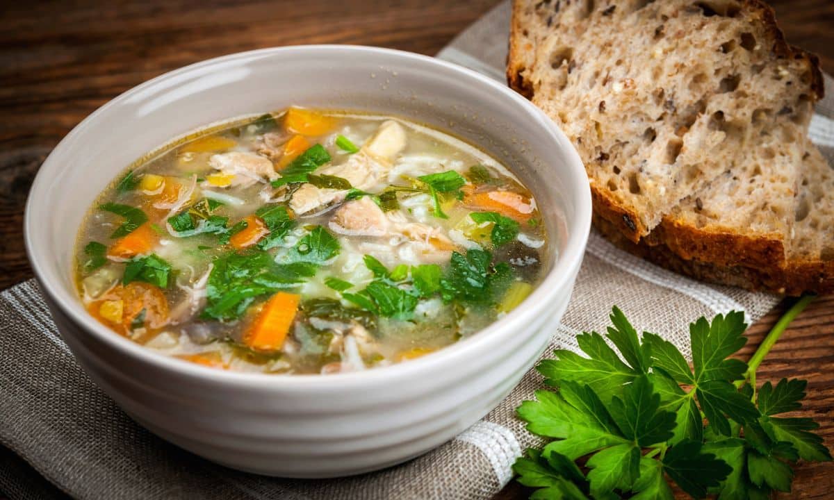 Tigela de sopa caseira com legumes, lentilha e frango servida no jantar.