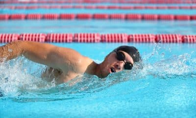 Pessoa nada crawl em piscina, virando a cabeça para respirar durante a braçada.
