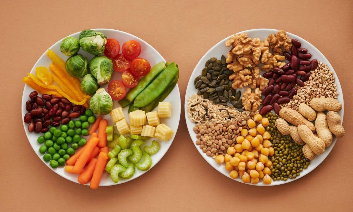mesa ou bancada com potes pequenos de feijão, lentilha, ervilha e grão-de-bico, ao lado de um prato simples com arroz, legumes e uma das leguminosas já preparada.