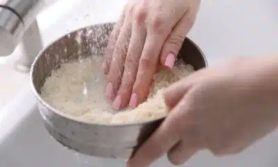 Pessoa lava arroz cru com água antes de colocá-lo para cozinhar.