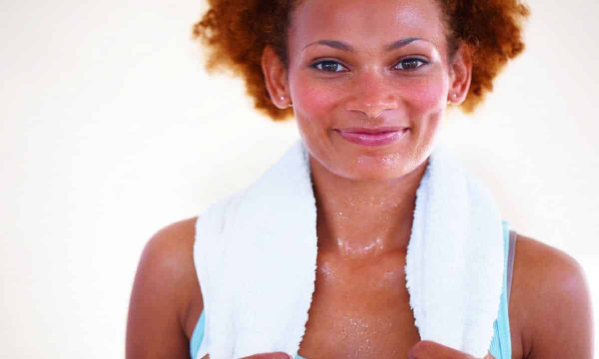 Pessoa adulta com o rosto corado descansa após realizar exercício físico.