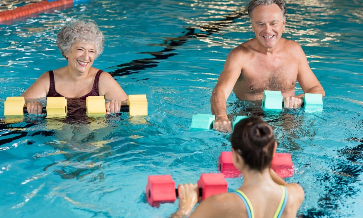Pessoas com mais de 60 anos fazem hidroginástica em piscina rasa